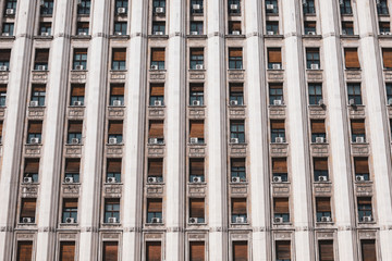 The exterior of an old soviet era style building with window air conditioning machines.