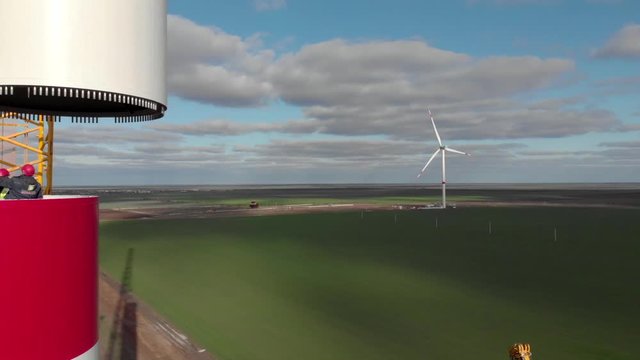Building process of wind energy power tower mill, under construction. Installation tower, workers inside assembling the pillar of windmill. Green, clean, renewable energy. Aerial footage.