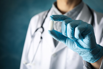 Doctor hold anal or vaginal candle on blue background, close up