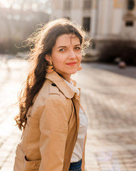 Beautiful young woman at city street. Happy tourist girl walking outdoors. Spring portrait of...