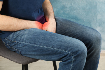 Man holds his crotch and sitting on chair. Urology