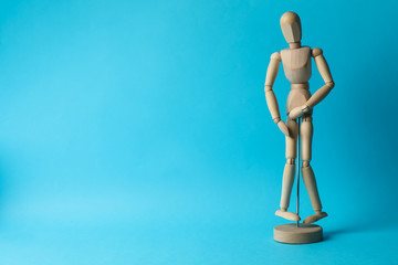 Wooden man hold his crotch on blue background. Urology
