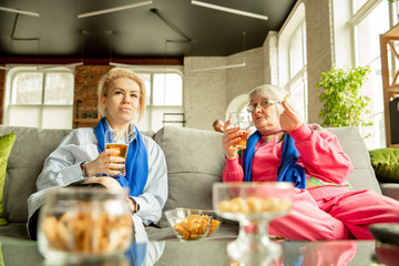 Excited family watching football, sport match at home. Grandma and daughter emotional cheering for national basketball, football, tennis, soccer, hockey team. Concept of emotions, support, cheering.