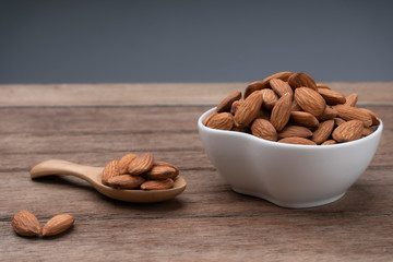 Almond nuts in wooden bowl and scoop isolated on rustic wood table background. Selective focus.