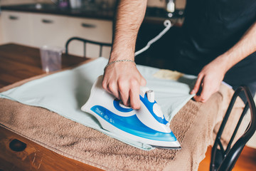 Unrecognizable male hand indoor at home ironing