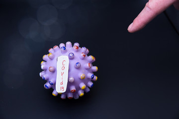 SARS-CoV-2 virus mockup. COVID-19 plate A finger points to a virus molecule. Dark background.