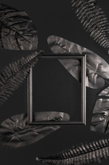 Black frame and black tropical leaves on a monochrome background. Trending template for design with copy space.