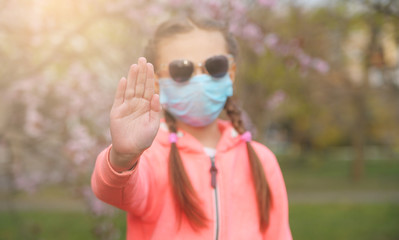 Little girl with protective medicine mask meets spring. Quarantine. Coronavirus pandemic.