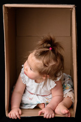 Fototapeta premium Little cute, beautiful girl sits in a box.