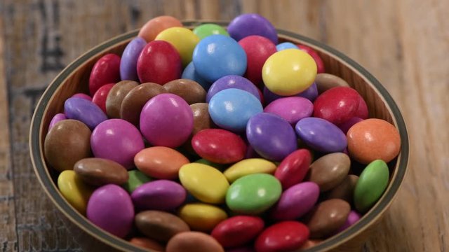 Colorful candies in a wooden bowl case isolated on wood background