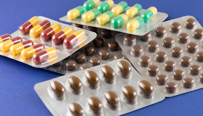 Side view of multi-colored pills and capsules in blister packs. The concept of the treatment of...