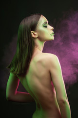 A beautiful slim topless girl with avant-garde makeup sensually poses covering her breast with her...
