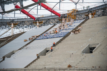 Stadium construction. Construction equipment and workers on the construction of a football stadium
