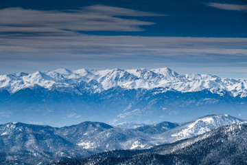 The famous snowed mountain of Parnassos, Voiotia, Greece, forest underneath fog, slopes with snow covered, cloudy atmosphere, beautiful conditions