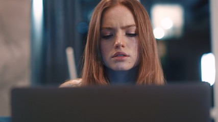 Close up portrait of beautiful serious redhair woman freelancer works in home typing email on laptop focused girl use computer for study online sitting on couch female user busy internet job social