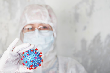 woman in protective suit holds coronovirus model
