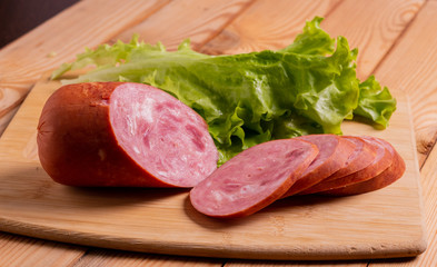 Slices of sausage, wheat bread and lettuce on a plate on the table close-up.