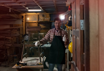 Handsome man wearing protective glasses,raise thump up and smile,for success his handmade wood work design,at home studio,Lens flare effect,blurry light around