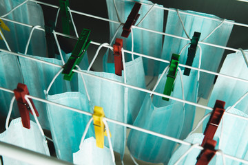 Lots of medical masks that are dried on the dryer on the clothespins. Concept of the problem of the shortage of face masks and other protective equipment against flu and virus, coronavirus.
