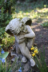 Kleiner Engel zwischen Blumen auf einem Grab im Fr&uuml;hling