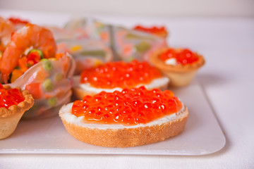 Fresh red caviar on bread on the plate. Sandwiches with red caviar. Delicatessen. Gourmet food.
