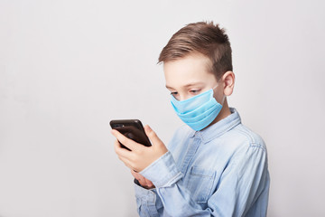Child in medical mask with mobile phone. Coronavirus and Air pollution pm2.5 concept. Virus symptoms. Concept of epidemic, influenza, protection from disease, vaccination. Flu illness. Medical care.