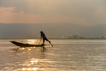 Fototapeta na wymiar Fishers on Inle Lake stand when they paddle their boats, moving the oar with their leg.