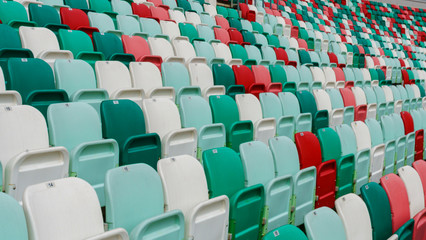 Naklejka premium Close-up empty multi-colored plastic seats with numbers at the stadium. Sport concept.