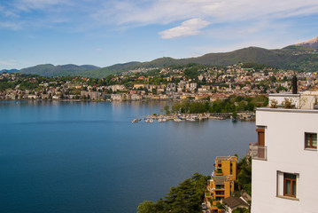 Fototapeta na wymiar View of the lake and the city of Lugano on a sunny summer day. Mountain landscape in the city of Lugano, Switzerland. 