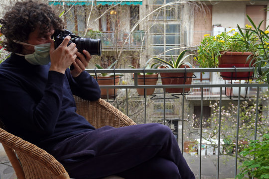 Europa, Italy , Milan - Man 40 years old with mask in quarantine at home - Smart work in apartment - taking pictures from the balcony and window