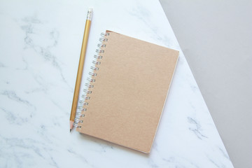 Top view of Notebook with gold pencil on marble background. 