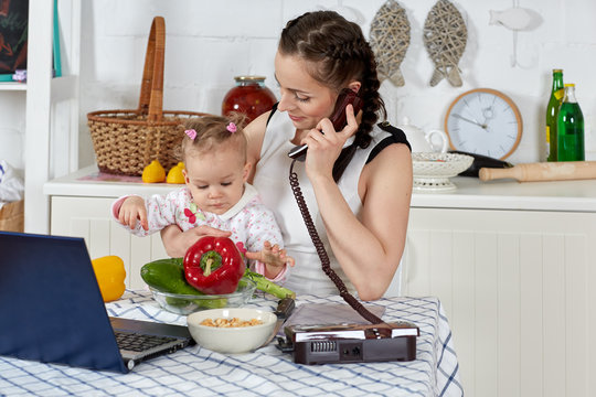 Mother with notebook and baby in kitchen. Isolation period, quarantine, social distancing. Remote education or remote work
