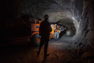 Man miner in underground quartz mine tunnel with scoop machine - obrazy, fototapety, plakaty