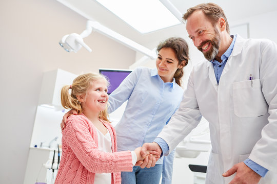 Frightened child salutes dentist with handshake