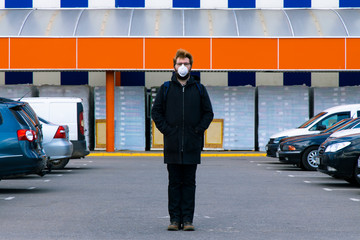 quarantine medical conditions concept picture lonely person in medicine mask in overcrowded parking place near shopping mall