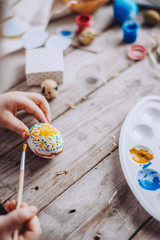 Happy easter! Cute little child girl painting with blue and yellow colors Easter eggs. family preparing for Easter. Hands of a girl with a easter egg. close-up