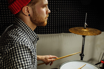 Fototapeta na wymiar young modern caucasian man professionally playing on drums. talented man in red hat play on drums, enjoy music. rock and roll, instruments concept