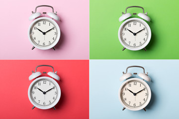 White vintage alarm clock on blue, pink, red and green backgrounds. Time concept