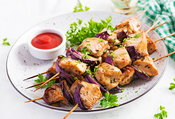 Grilled chicken kebab with red onions on a light table. Grilled meat skewers, shish kebab on light background.