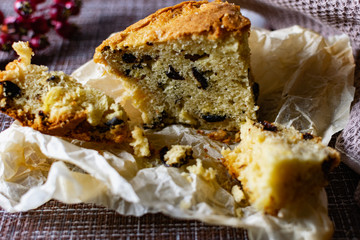 A large piece of homemade pie with prunes filling. orange and Apple, cut on parchment paper. Porous pastry like a cupcake with pieces of berries and fruit, next to delicious crumbs of sponge cake