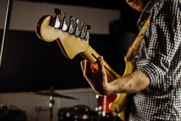 close-up photo of young man holding electric guitar, talented musician perform music in studio, preparing for concert