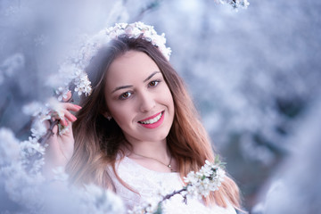Happy smiling pretty young woman with spring flowers at garden - 334208879