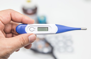 Pills and medical thermometer on white background