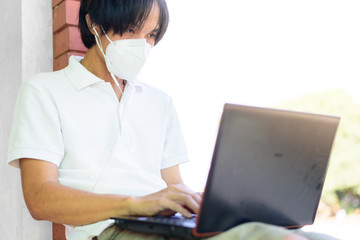 Work from home / The man wear N95 mask and use laptop for work from home in corona virus critical time