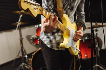 cropped caucasian man perform music with the use of electric guitar, handsome guy in recording...