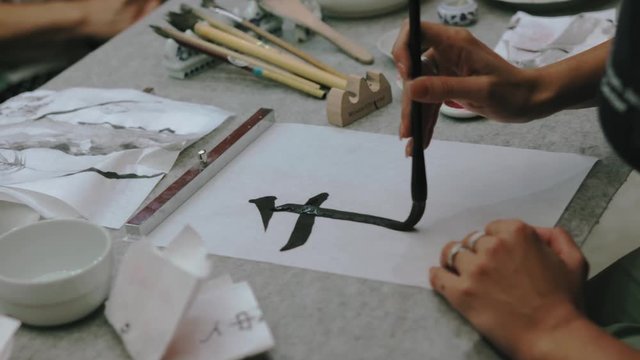 Women hands painting Japanese style. Traditional Japanese calligraphy and drawing sumi-e