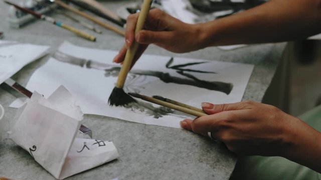 Women hands painting bamboo Japanese style. Traditional Japanese calligraphy and drawing sumi e