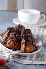Dessert. Cookies with chocolate topping on a white plate. Anthill. Chocolate, strawberry and cup of tea on a light grey background. Background image, copy space