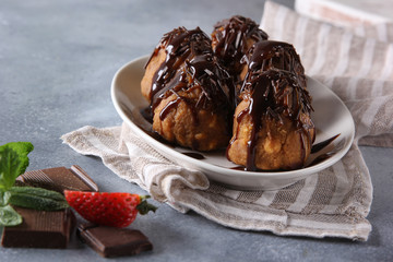 Dessert. Cookies with chocolate topping on a white plate. Anthill. Chocolate, strawberry, mint on a light grey background. Background image, copy space