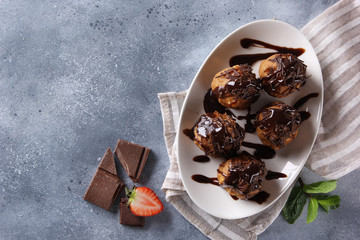 Dessert. Cookies with chocolate topping on a white plate. Anthill. Chocolate, strawberry, mint on a light grey background. Background image, copy space